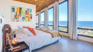 A spacious bedroom with a large bed, a view of the ocean, and a wooden ceiling. - Villa Coco Palm - Oasis de Luxe 5*- Magnificent Sea View, Private Pool & Jacuzzi (Saint-Pierre)