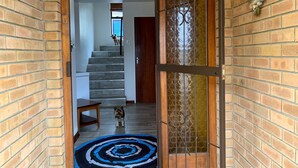 A brick-walled hallway with a wooden door, a small rug, and a dog on the stairs. - Spectacular Views of the bay -Bay View Witsand (Witsand)