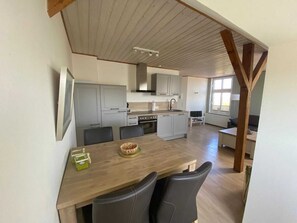 Una cocina moderna con armarios grises, una mesa de comedor de madera y sillas negras.