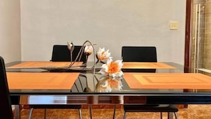 Un salón de conferencias con una mesa de vidrio, dos sillas y un jarrón con flores.