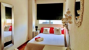 Una habitación de hotel con cama, mesita de noche, espejo y ventana.