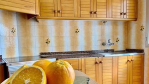 Una cocina con armarios de madera, encimera de granito y un plato de vidrio con naranjas.