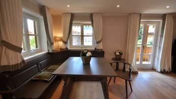 A room with a wooden table, benches, and a window with curtains.