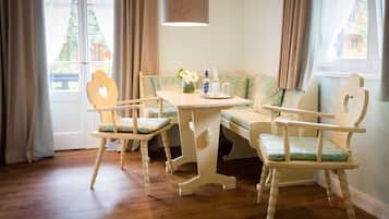Una habitación con suelo de madera, una mesa con sillas, un banco y una lámpara colgante.