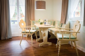 A room with a wooden floor, a table with chairs, a bench, and a hanging lamp. - Suite mit Bergblick - Bio Design Boutique Hotel Landhaus St. Georg (Bad Wiessee)