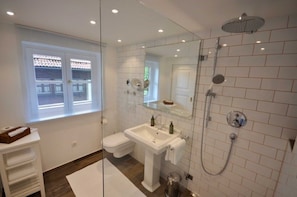 A bathroom with a toilet, sink, shower, and a glass partition.