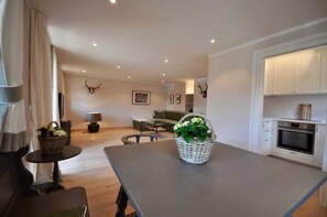 A modern living room with a dining table, sofa, and kitchen area. - Suite mit Bergblick - Bio Design Boutique Hotel Landhaus St. Georg (Bad Wiessee)