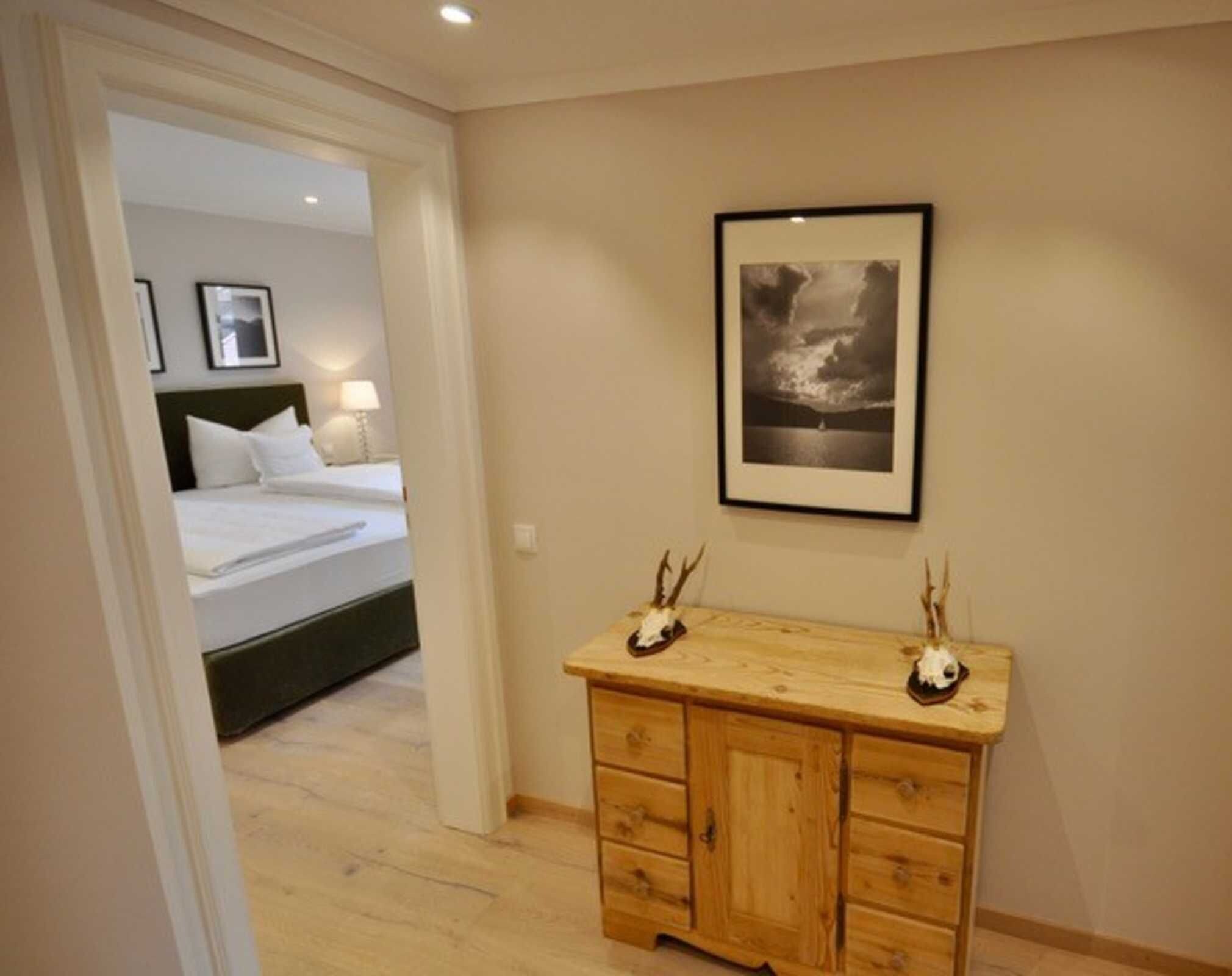 Ein Hotelzimmer mit einem Bett, einer Holzkommode und einem gerahmten Bild an der Wand.