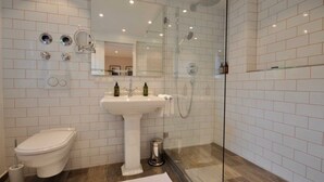 Un baño moderno con inodoro, lavamanos y ducha con mampara de vidrio.