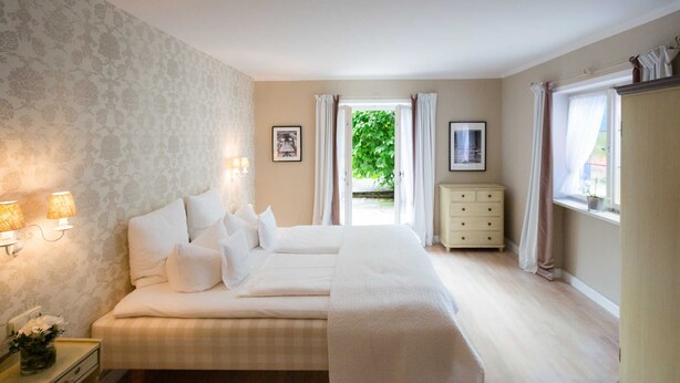 Un dormitorio con cama, lámparas de noche, cómoda y ventana con cortinas.