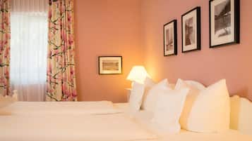 Ein Hotelzimmer mit zwei Betten, einem Nachttisch mit Lampe und drei gerahmten Bildern an der Wand.