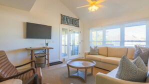 A living room with a sofa, a coffee table, a TV, a ceiling fan, and a sign that reads "BEACHHOUSE". - 2 Mins to Beach; Community Pool & Pickleball; Dog Friendly; Walk to Grocery, Shops & Restaurants! (Isle of Palms)