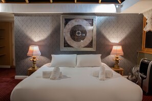 Quarto de hotel com uma cama grande, duas luminárias de cabeceira, um aquecedor e uma parede com padrão geométrico.