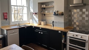 Eine moderne Küche mit Geschirrspüler, Backofen und einem Fenster mit Blick auf eine Holzterrasse.