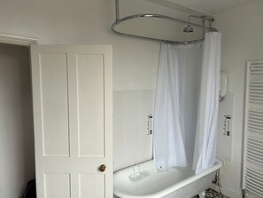 Ein Badezimmer mit einer weißen Badewanne, einer Duschvorhang und einer Tür.