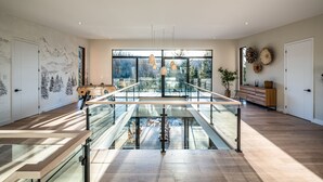 Ein geräumiges Zimmer mit einem Glastisch, modernen Pendelleuchten und Blick ins Freie.