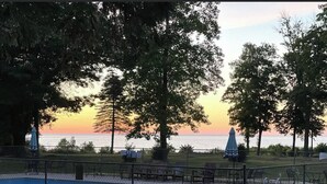 Una piscina cercada, rodeada de árboles y con vista al atardecer sobre el agua.
