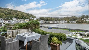 Ein Restaurant am Meer mit Außenbereich, das auf einen Hafen, die Stadt und anlegende Boote blickt.