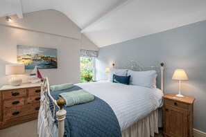 Une chambre à coucher avec un lit, des tables de chevet, une commode et un tableau au mur.