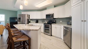 A modern kitchen with white cabinets, stainless steel appliances, and a central island with bar stools.