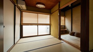 Perinteinen japanilainen huone, jossa on tatamimatto, liukuvat shoji-ovet ja puinen katto.