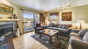 A living room with a fireplace, a sofa, a coffee table, and a view through a sliding glass door.