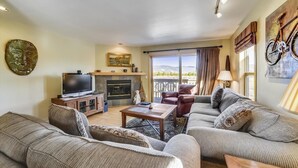 A living room with a fireplace, leather sofa, and a television.