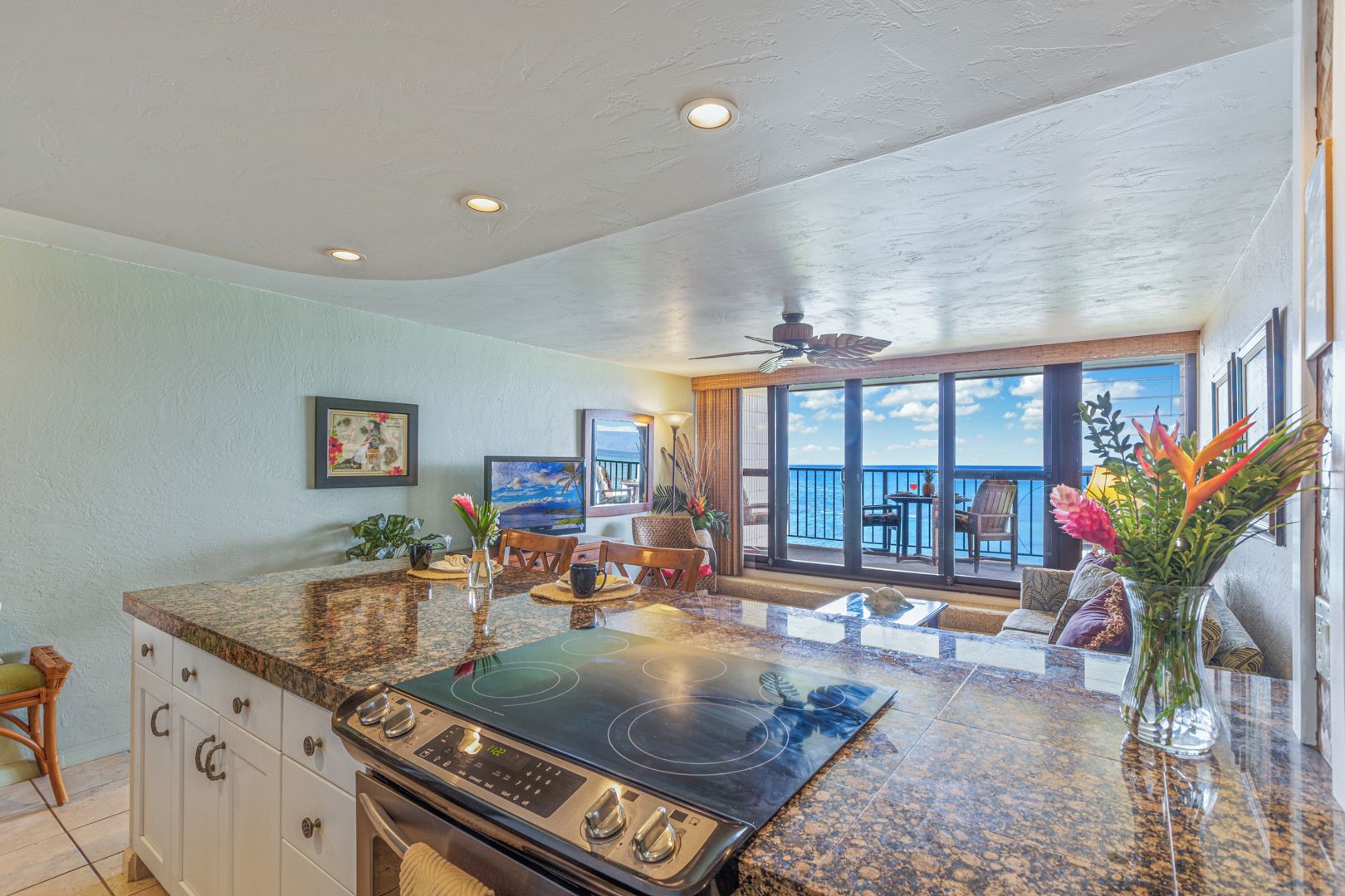 A kitchen with a large island, a stove, and a dining area with a view of the ocean.