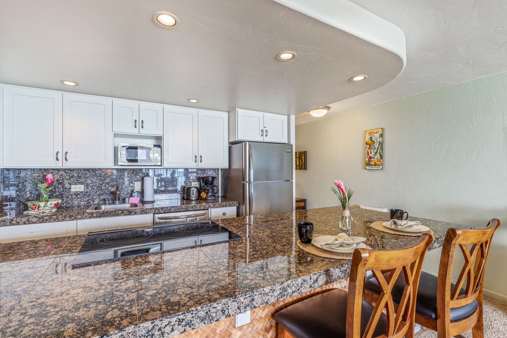 A modern kitchen with white cabinets, granite countertops, stainless steel appliances, and a dining area with wooden chairs and a table.