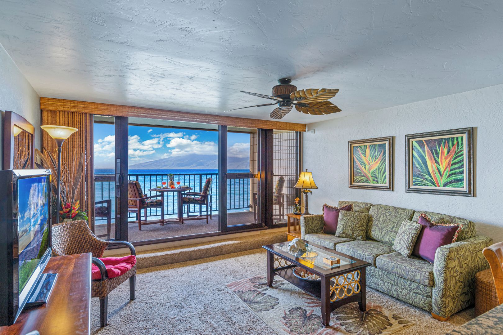 Un vaste espace de vie avec un balcon donnant sur l’océan, aménagé avec un canapé, des fauteuils et une table basse.