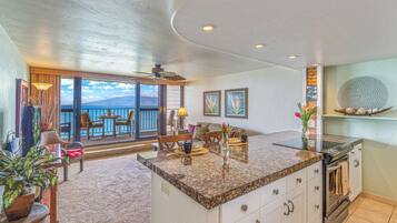 A spacious living area with a large window overlooking the sea, a kitchen with granite countertops, and a dining area with a view.