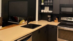 A modern kitchen with a dishwasher, oven, and a built-in microwave. - Bohemian Sunrise  (Englewood)