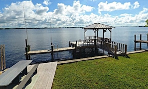 Relax on the lakeside dock, surrounded by a serene grassy area and a tranquil shoreline.