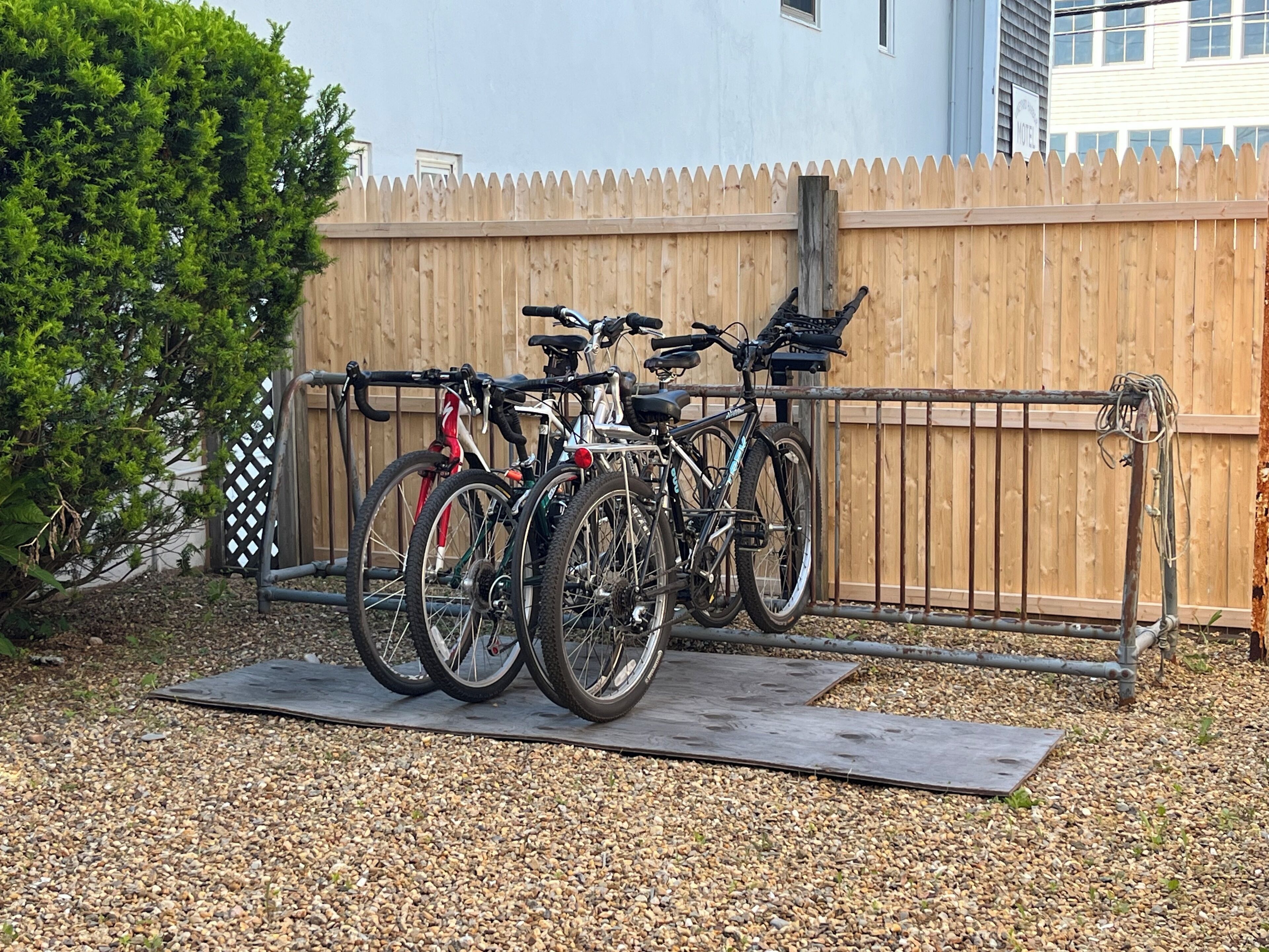 Bicycles parked on a mat in front of a wooden fence.