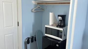 Cocina compacta equipada con microondas, cafetera y perchero.