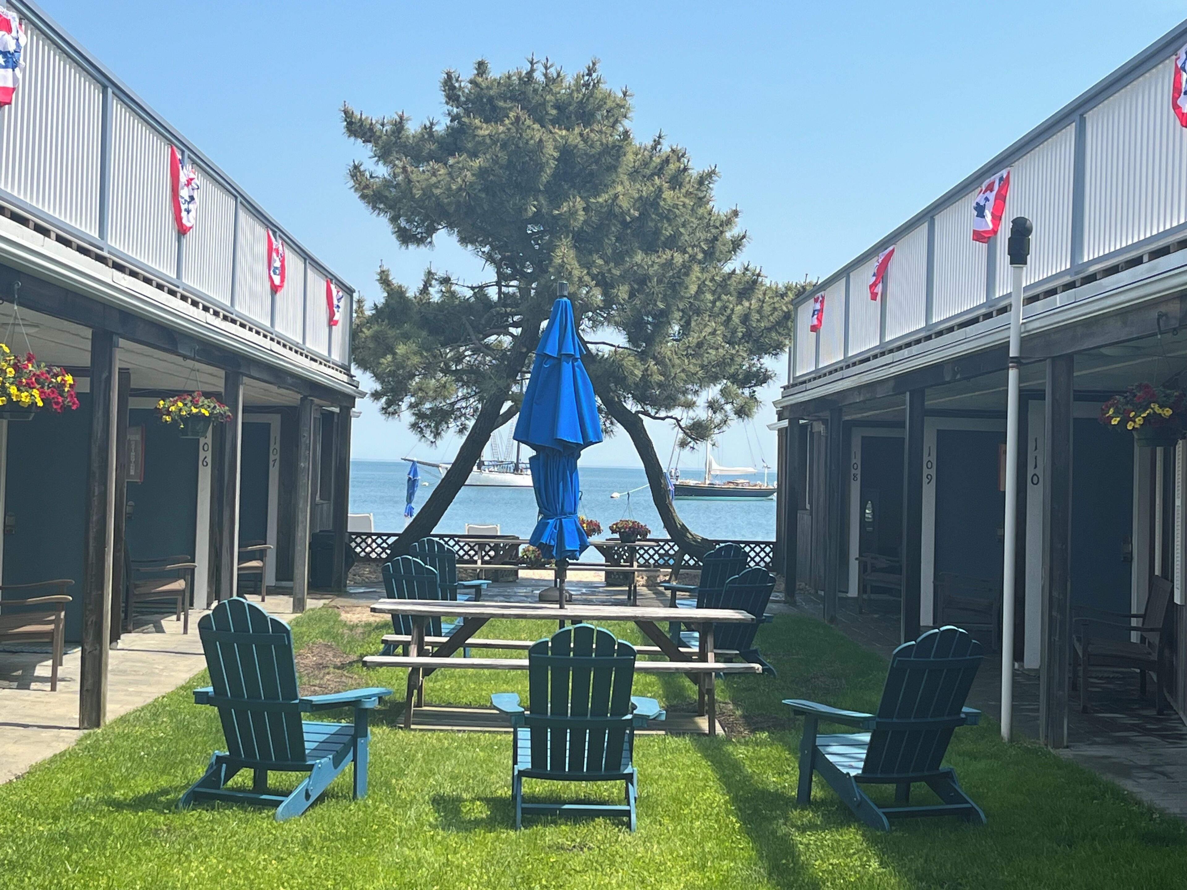 Zona de pati amb cadires Adirondack, un parasol blau i vista a l'oceà.