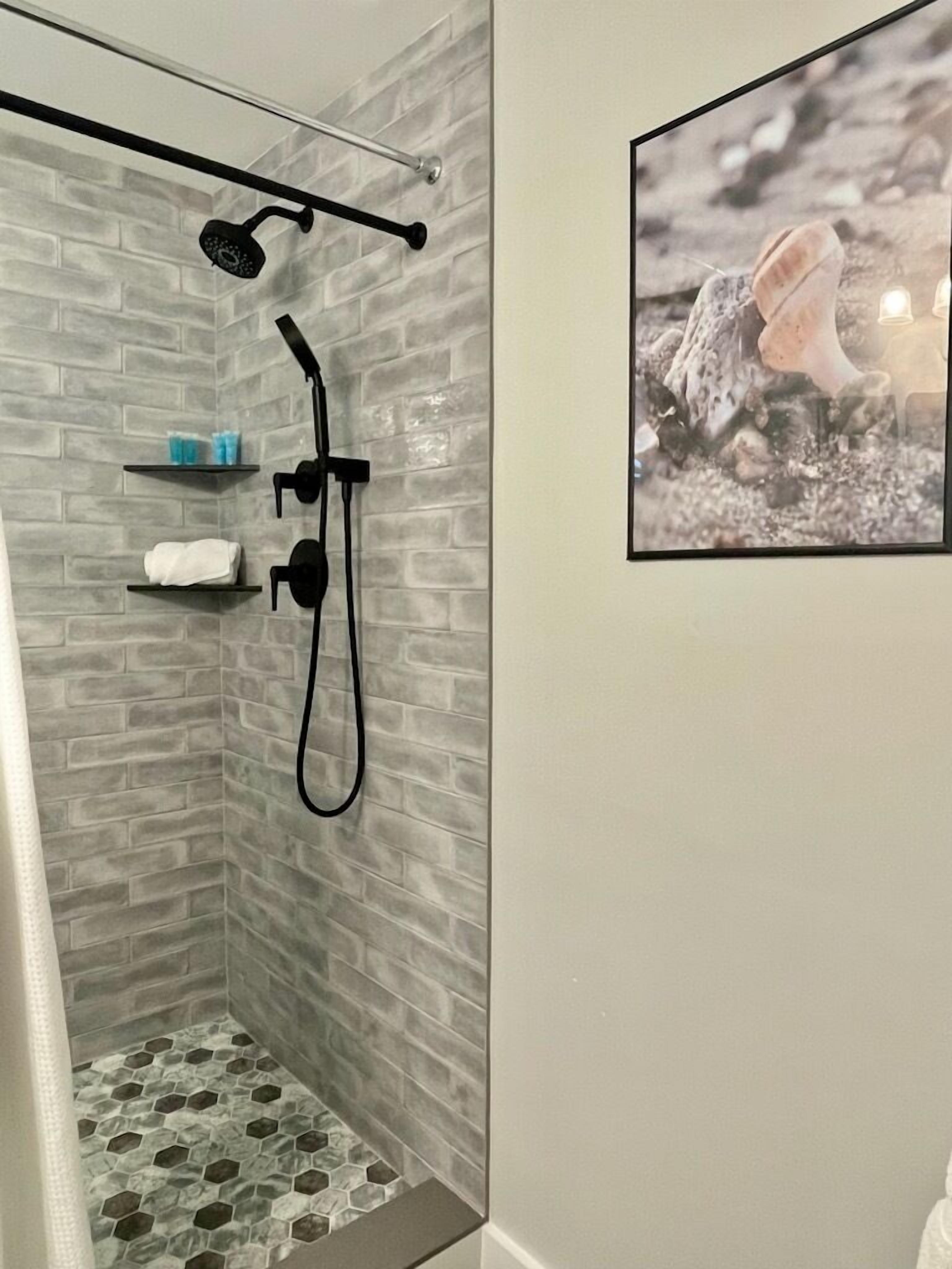 A shower with a glass door, a towel rack, and a shelf with toiletries.