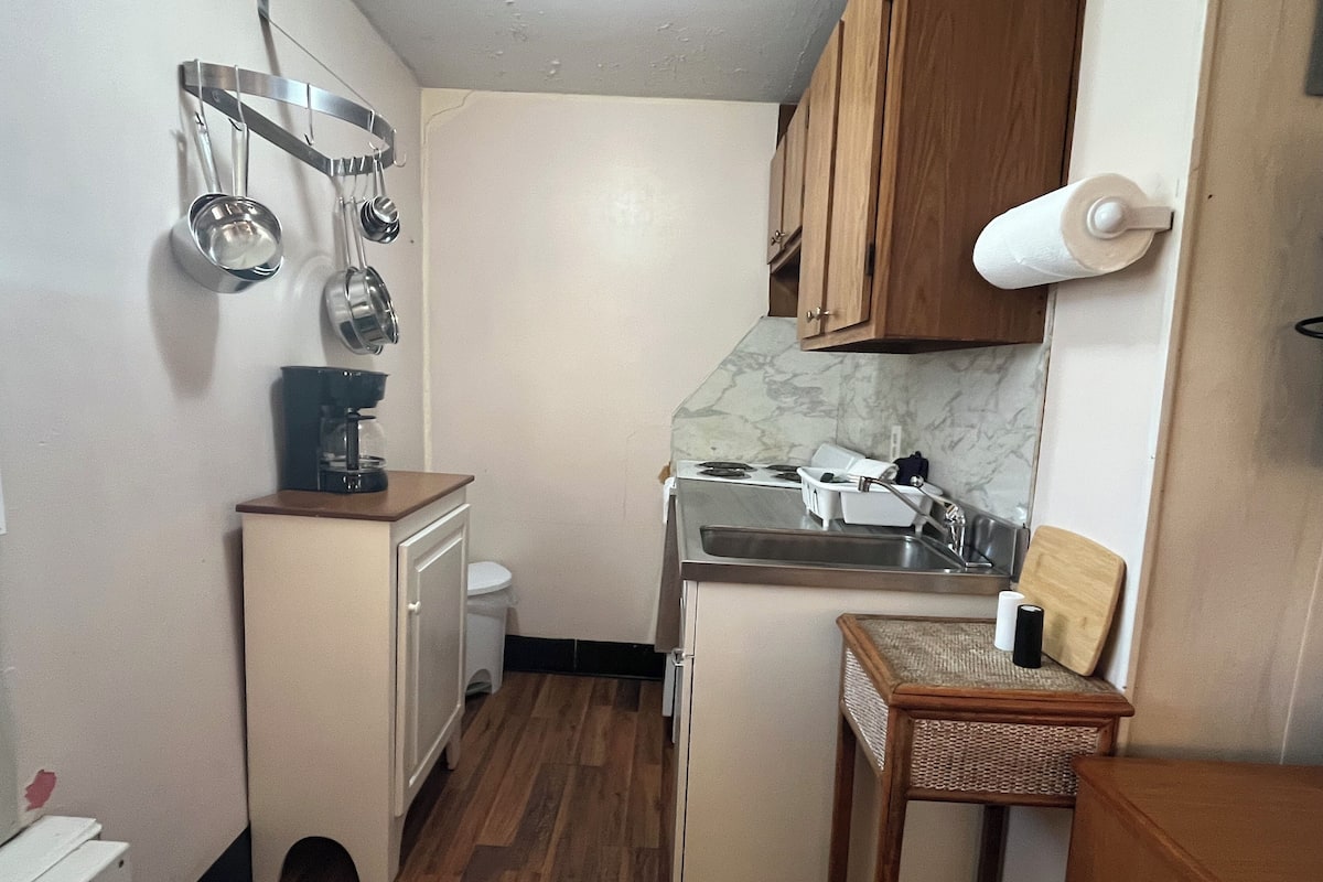 A compact kitchen with a stove, sink, and a small dining area.