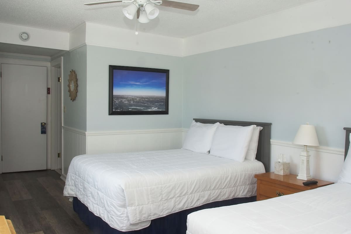 A hotel room with a large bed, a bedside table with a lamp, and a framed picture on the wall.