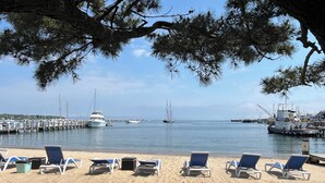 A beach with lounge chairs and a marina in the background. - Vineyard Harbor Motel - Private Beach (Vineyard Haven)
