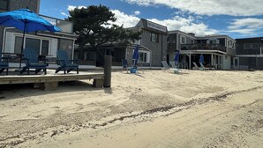 A beachside motel with outdoor seating and umbrellas, a tree, and a clear sky. - Vineyard Harbor Motel - Private Beach (Vineyard Haven)