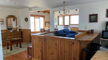 A spacious living area with a wooden island, a blue sofa, and a dining table.