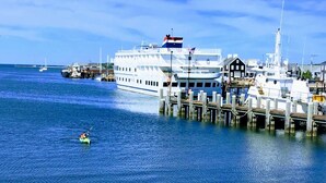 A waterfront scene with a large white cruise ship docked at a pier, surrounded by smaller boats and buildings. - Vineyard Harbor Motel - Private Beach (Vineyard Haven)