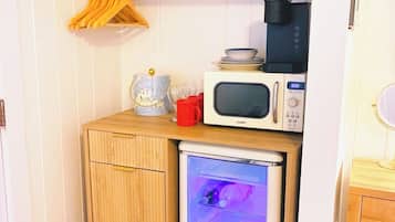 Een kleine keuken met een koelkast, magnetron en koffiezetapparaat.