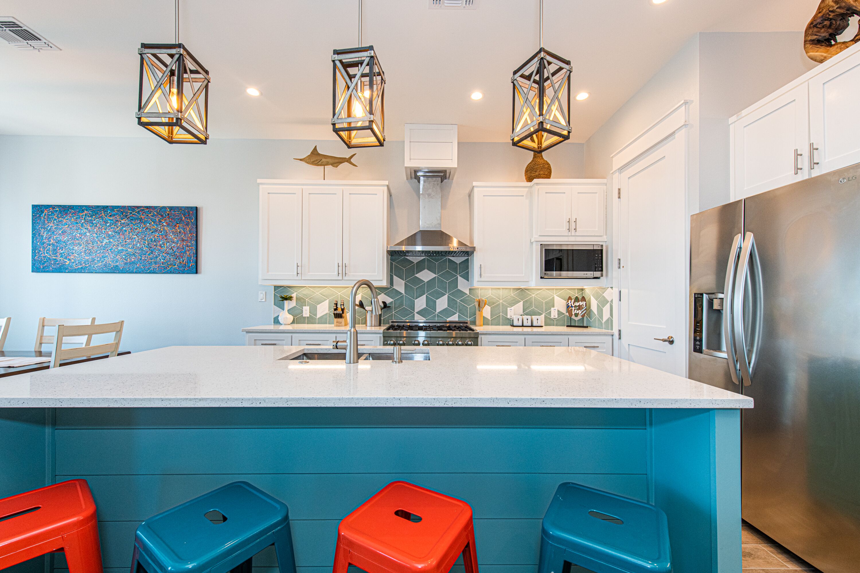 A modern kitchen with a central island, bar stools, and pendant lighting.