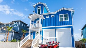 Une maison à deux étages, avec une façade bleue, des boiseries blanches et un garage.