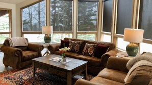 A spacious living room with a large window, a brown leather sofa, a coffee table, and two lamps. - Mt. Crested Butte Full House, 3 Bedroom/3.5 Bath+Loft, Hot Tub, Shuttle  to Ski (Crested Butte)