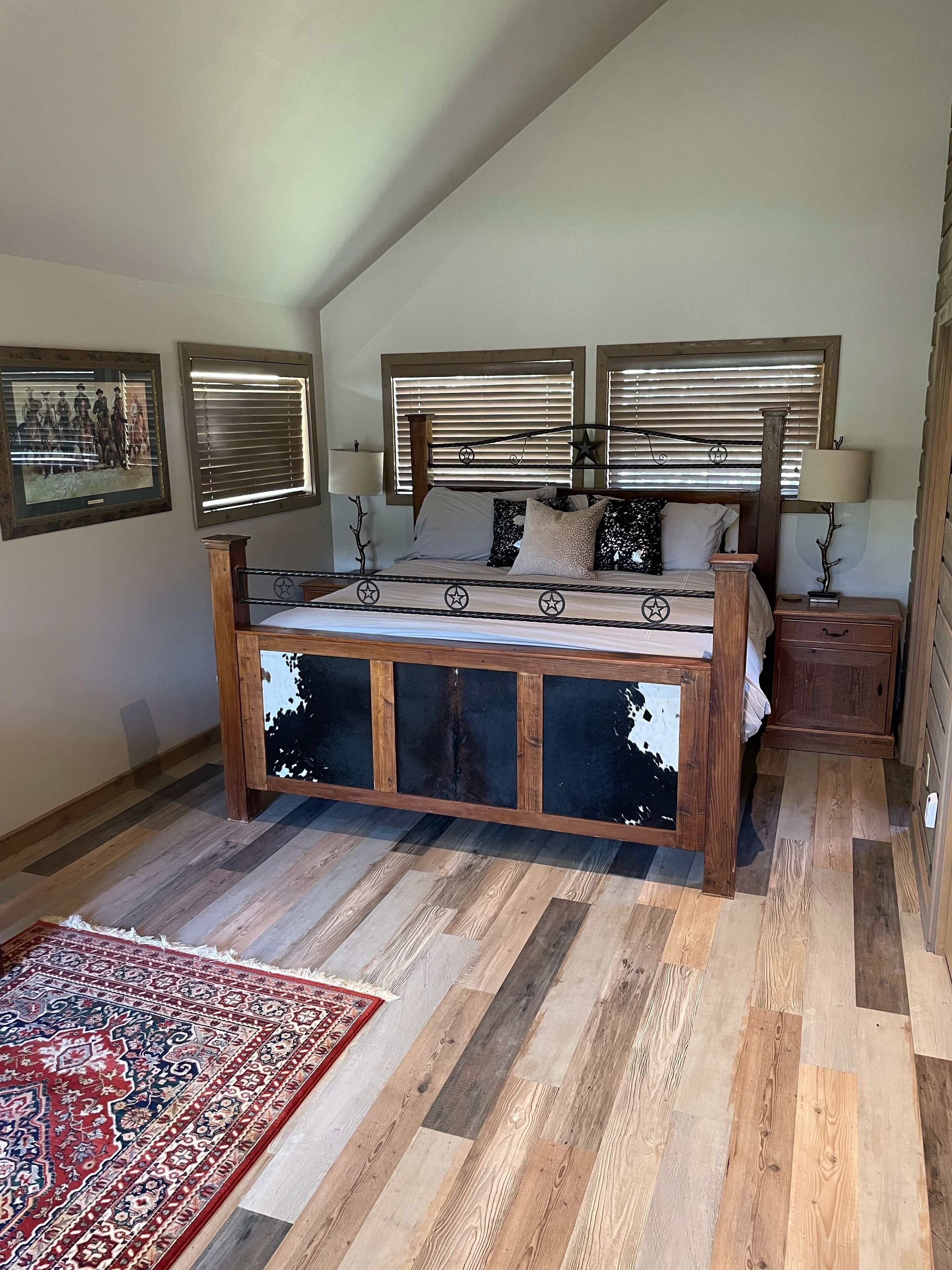Un dormitorio con una cama de madera, un espejo grande y una alfombra roja con estampado.