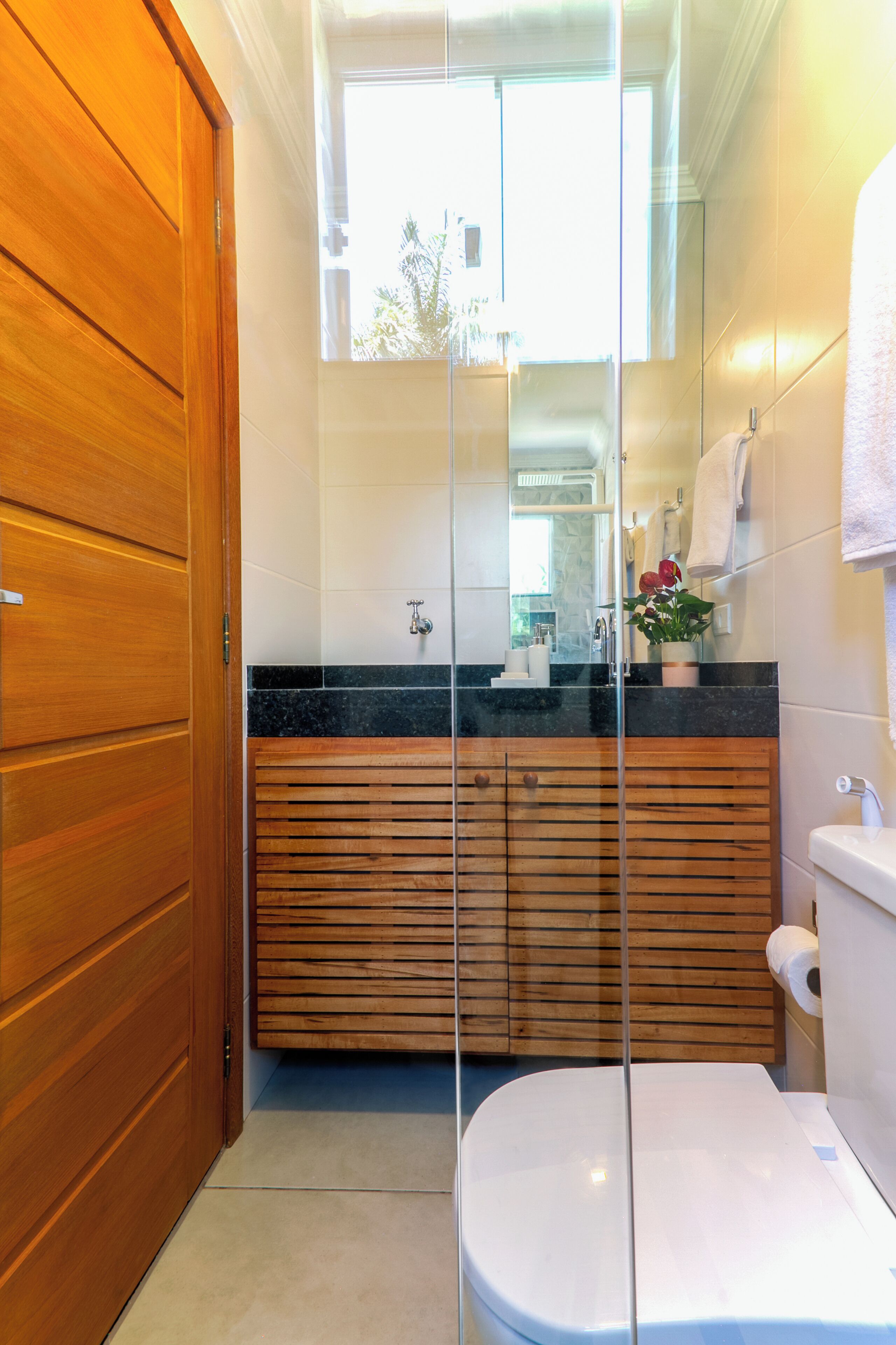 A bathroom with a wooden vanity, a white toilet, and a glass shower enclosure.