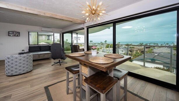 Ein modernes Wohnzimmer mit einem großen Esstisch, Barhocker und Blick auf die Stadt.